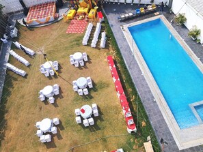 A pool area with multiple seating arrangements and a covered section. - Hotel Shubh Villas (Jaipur)