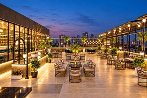 Un bar situat a la terrassa amb seients exteriors, vistes a la ciutat i decoració moderna.