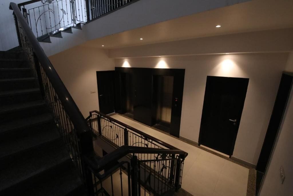 Interior com vários níveis, incluindo uma escadaria, área plana com portas e iluminação embutida.