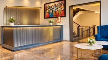 Un área de recepción con un mostrador moderno, una escalera y un sofá azul.