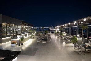 An outdoor terrace with seating areas, potted plants, and a glass railing. - Hotel Shubh Villas (Jaipur)