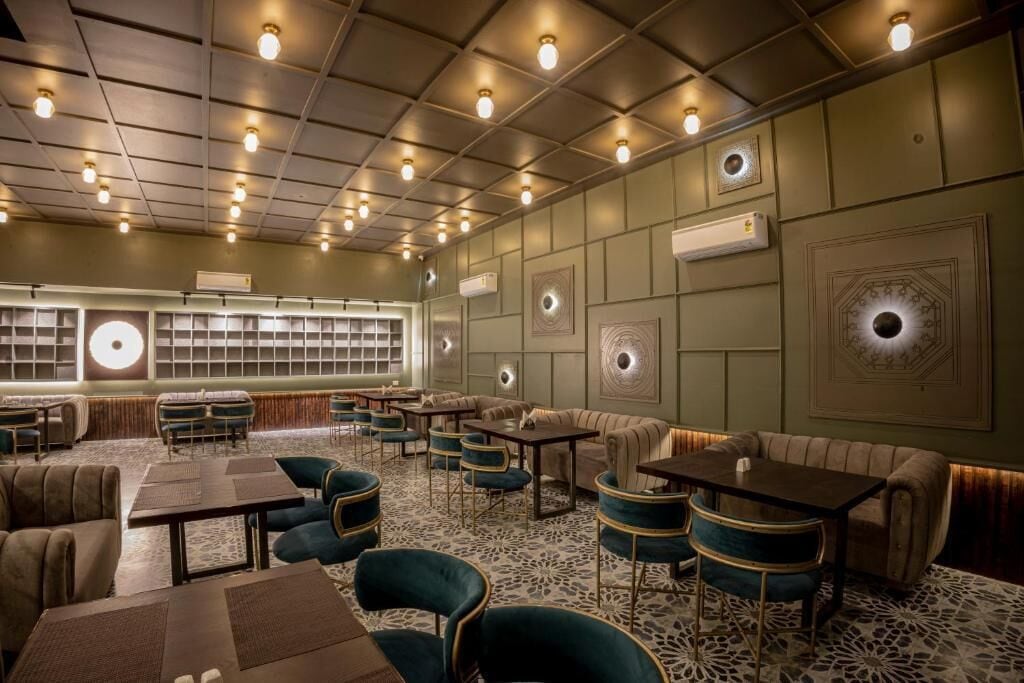 A spacious lounge area with multiple seating options including sofas and tables, a patterned carpet, and a ceiling with recessed lighting.