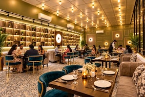 Un restaurant amb diverses taules i cadires, un paviment amb dibuixos i una paret amb plantes en testos.