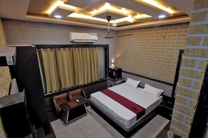 A hotel room with a large bed, a desk, a chair, a nightstand, a lamp, and a ceiling fan.