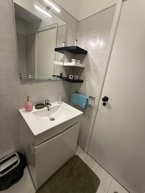 A bathroom with a white sink, a mirror, a towel rack, and a door. - Apart Lisbon Airport (Lisboa)