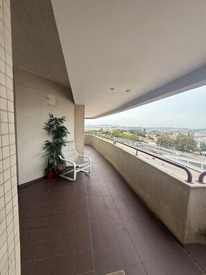 A balcony with a chair, a potted plant, and a view of a cityscape. - Apart Lisbon Airport (Lisboa)