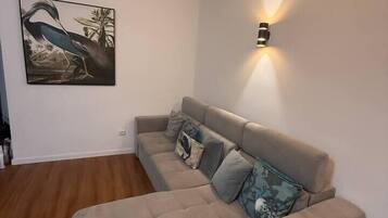 Ein Ecksofa mit einer Wandleuchte und einem gerahmten Bild.