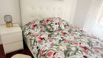 Ein Schlafzimmer mit einem Bett, einem Nachttisch, einer Lampe und einem weißen Teppich.