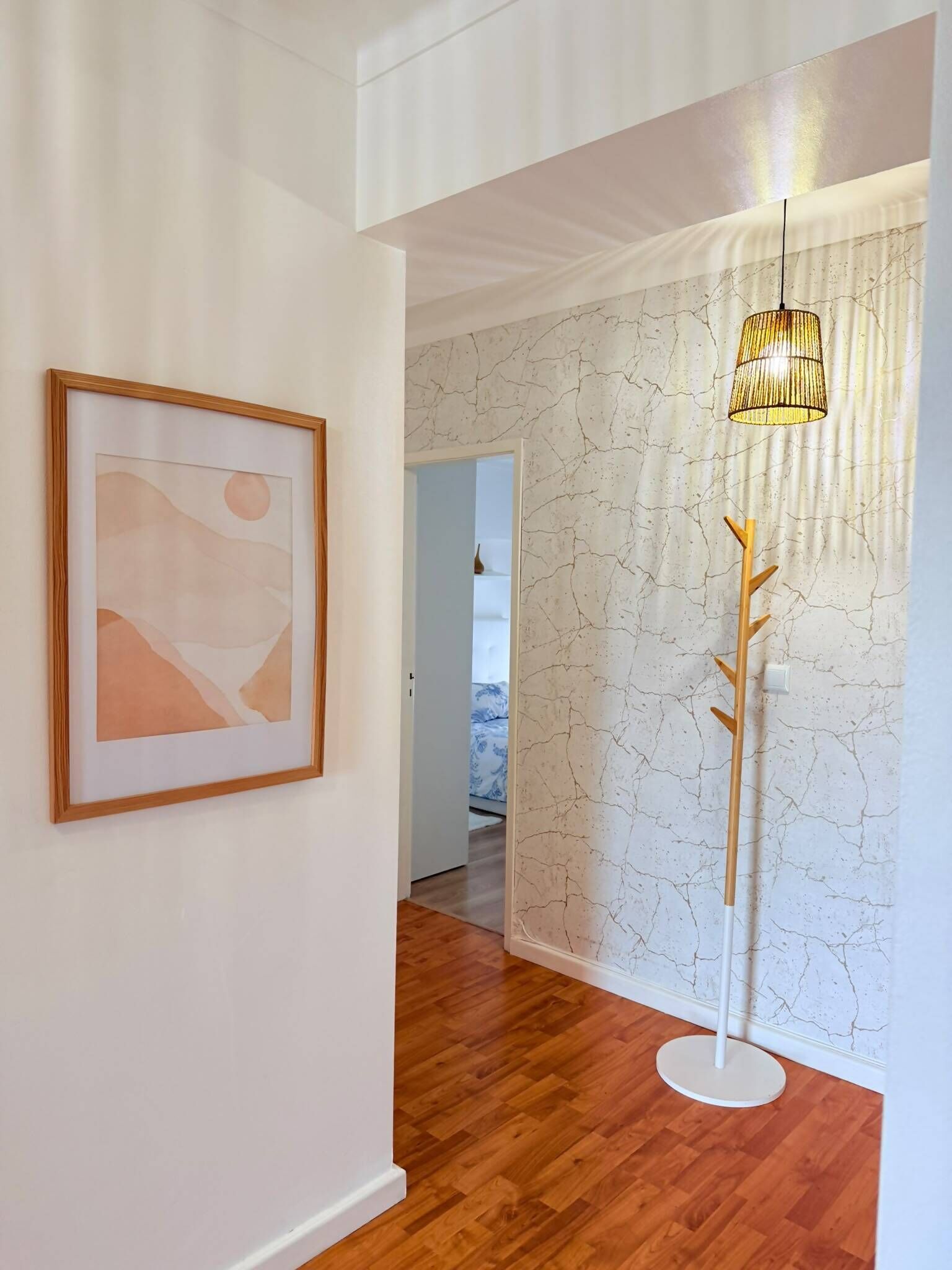 Ein Korridor mit Holzboden, einem gerahmten abstrakten Gemälde, einer strukturierten Wand und einer Stehlampe.