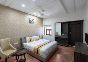 A hotel room with a bed, a chair, a small table, a wardrobe, and a television. - Hotel Ramdev (Pokhran)
