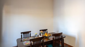 Comedor con una mesa dispuesta para cuatro, sillas, un ventilador de techo y un enchufe de pared.