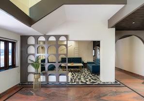 A modern interior with a geometric patterned floor, a seating area with a sofa and a table, and a decorative wall with circular cutouts.