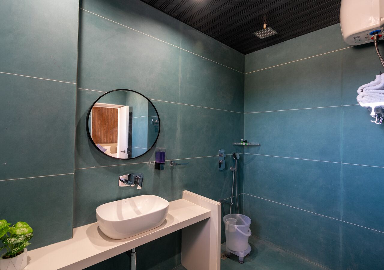 A bathroom with a round mirror, a white sink, and a shower area.