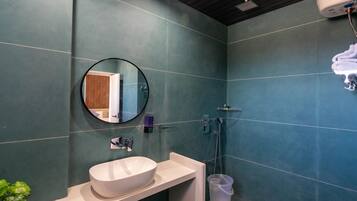 A bathroom with a round mirror, a white sink, and a shower area.