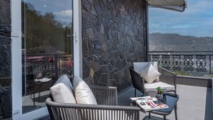 A balcony with wicker furniture, a stone wall, and a view of a cityscape.