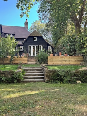 A black house with white-framed windows, a stone staircase, and a wooden fence.