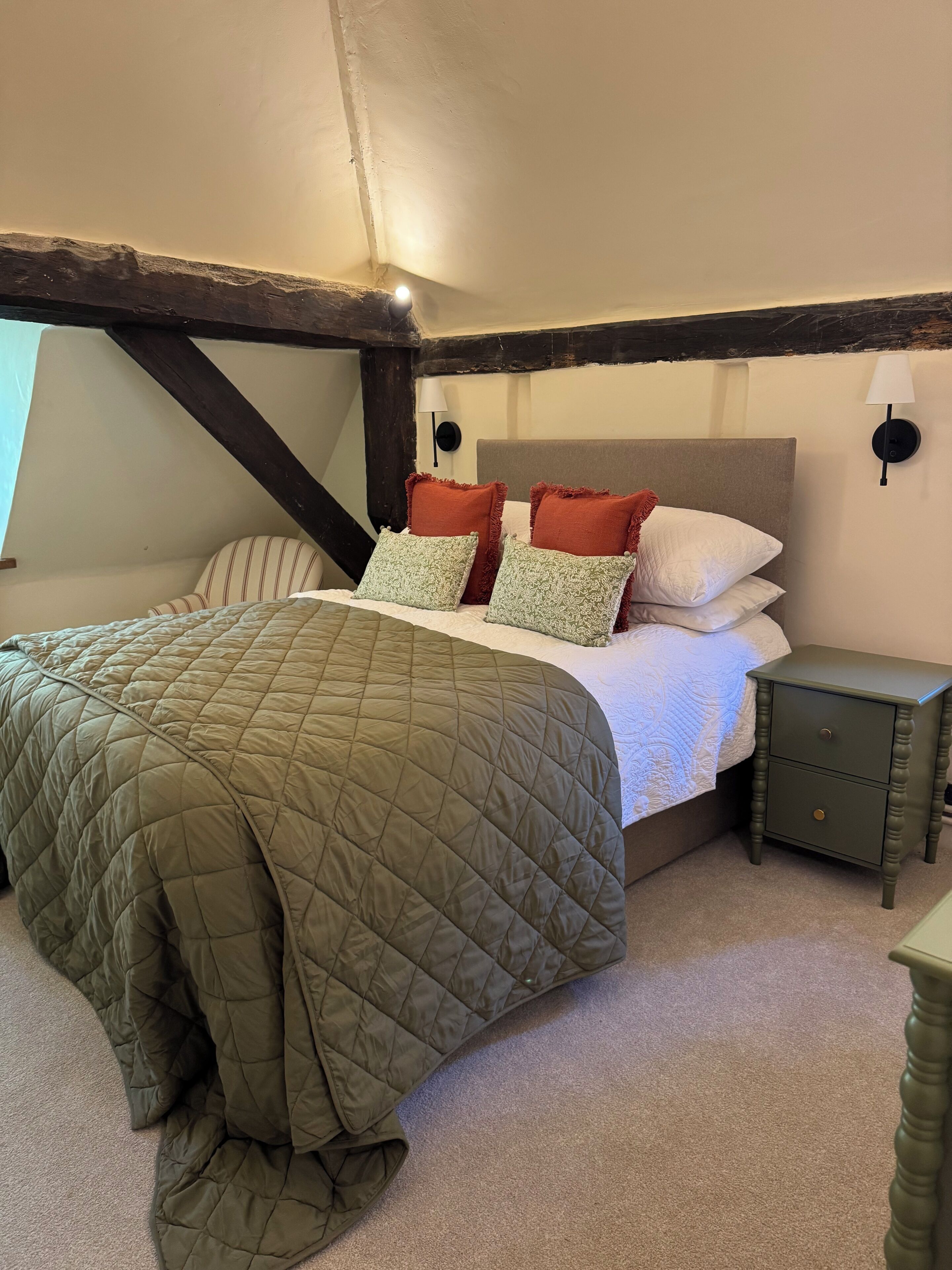 Een slaapkamer met een bed, nachtkastje en lamp.