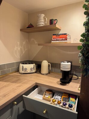 A kitchen with a toaster, coffee maker, and a drawer with coffee pods.