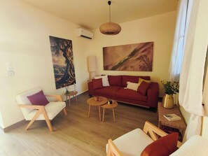 Un salon avec un canapé, un fauteuil, une table basse et un tableau accroché au mur.