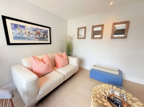 Uma sala de estar com sofá, mesa de centro e um quadro emoldurado.
