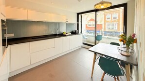 Una cocina moderna con armarios blancos, una encimera negra y una zona de comedor con mesa y sillas.