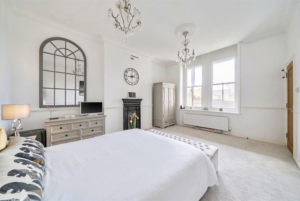 Een slaapkamer met een groot bed, een dressoir, een televisie, een open haard en een raam met uitzicht.