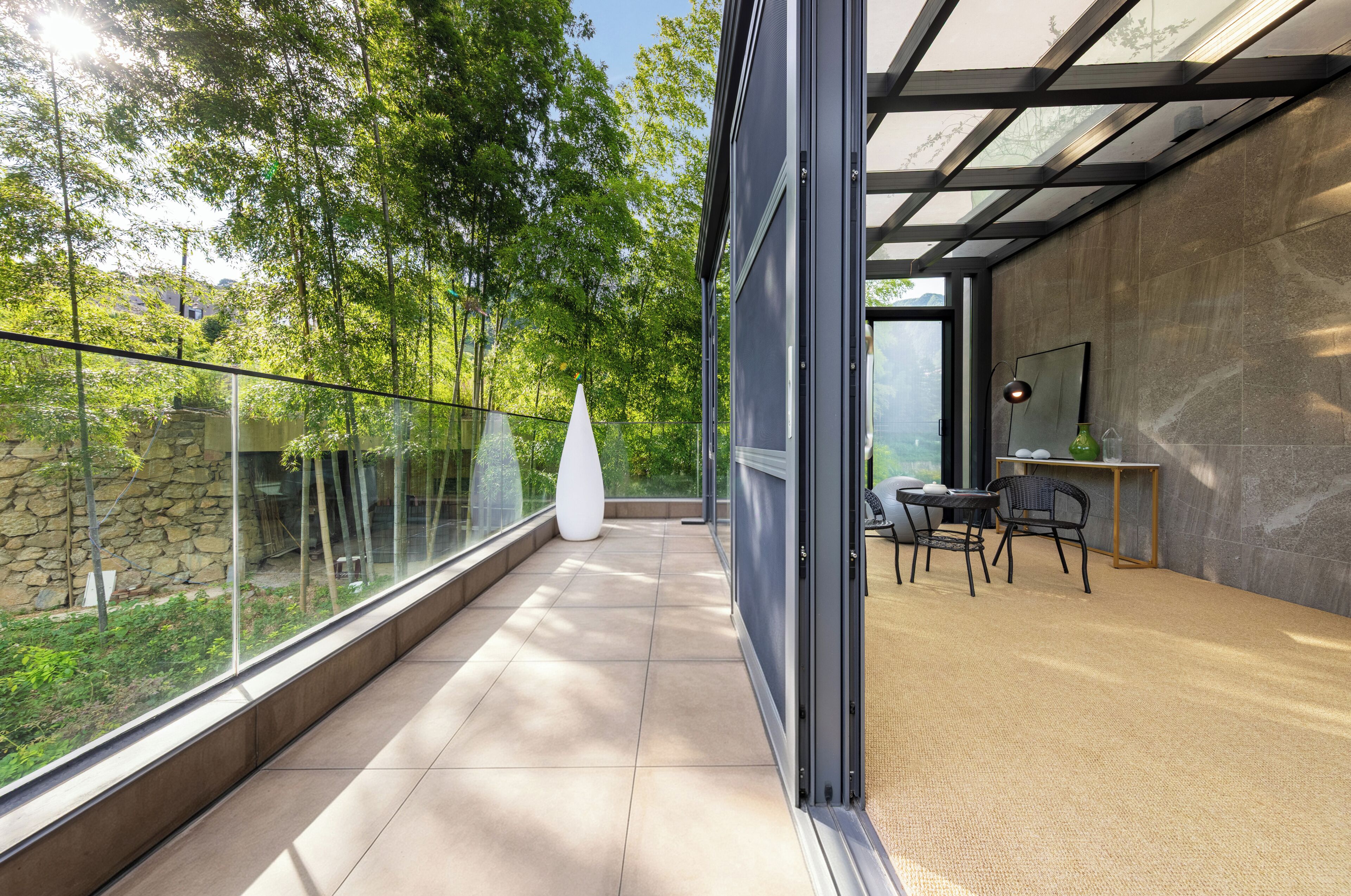 A modern interior with a glass balcony, a white vase, and a dining area with chairs and a table.
