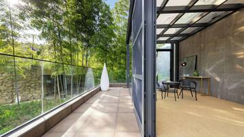 A modern interior with a glass balcony, a white vase, and a dining area with chairs and a table.