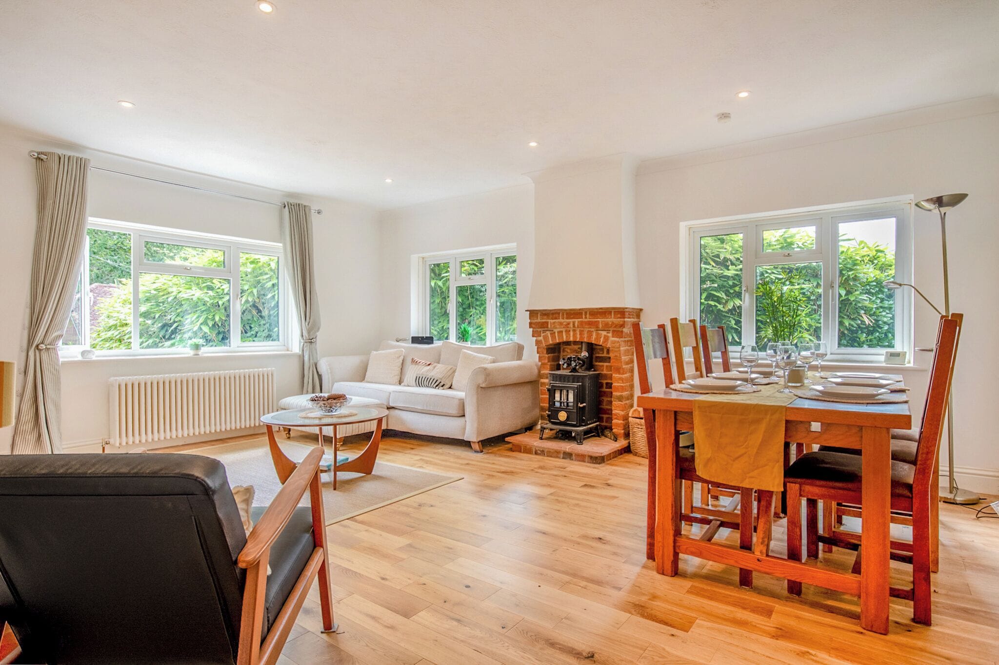 A spacious living room with a fireplace, a dining area with a table set for four, and a sofa.