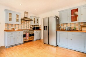 Eine Küche mit hellblauen Schränken, einem Edelstahl-Kühlschrank, einem eingebauten Backofen und einer Holz Arbeitsplatte.