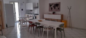 Eine moderne Küche mit weißen Schränken, einem Esstisch mit Stühlen und einer Weltkarte an der Wand.