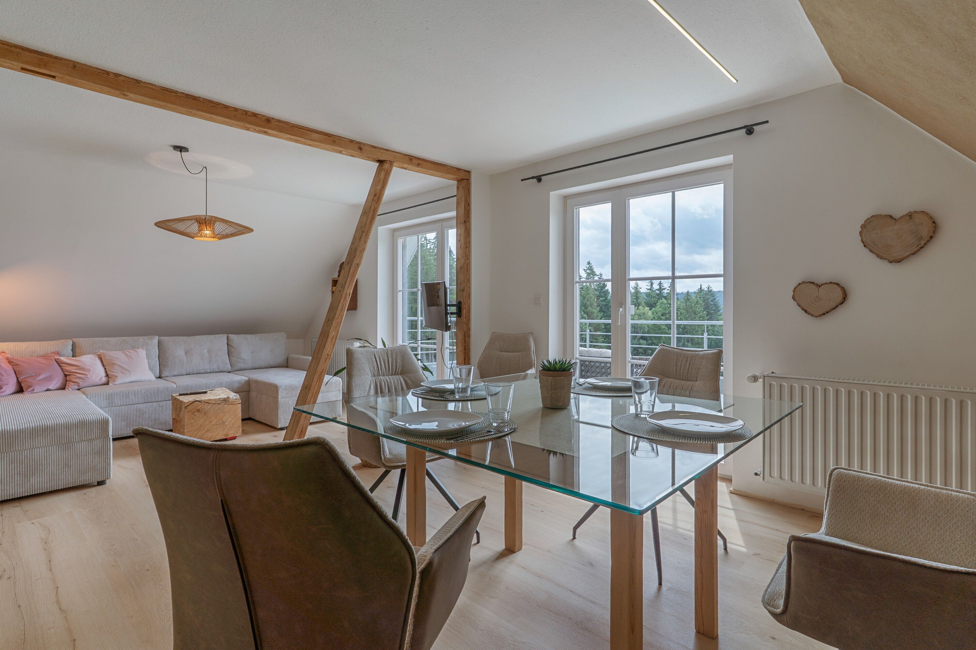 Ein modernes Wohnzimmer mit einem Glastisch, einer Couch und Blick ins Freie.