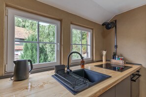 A modern kitchen with a black sink, a kettle, and a bottle of dish soap.