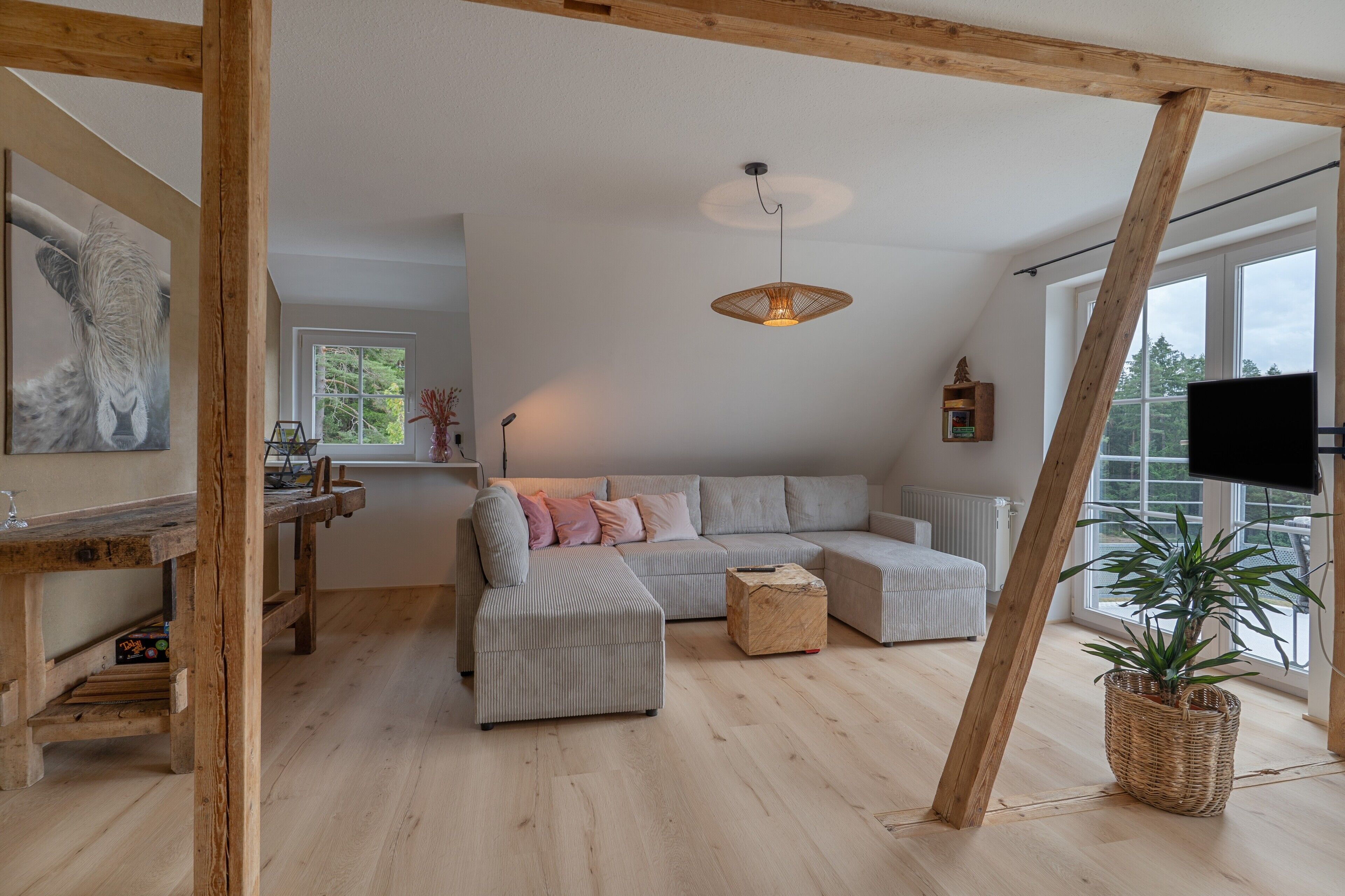 Un salon moderne avec un canapé d’angle, une petite table basse et une grande fenêtre qui laisse entrer la lumière naturelle.