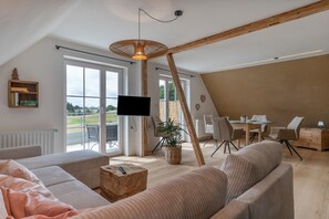 A spacious loft with a large window, a dining area, and a cozy seating area.