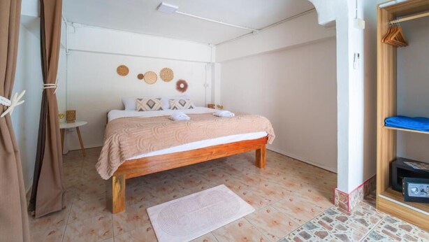 A bedroom with a wooden bed, a small bedside table, and a wall-mounted shelf.