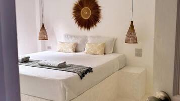 A bedroom with a bed, a wall-mounted sunburst decoration, and two hanging pendant lights.