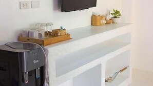 A modern kitchen with a built-in water dispenser, a flat-screen TV mounted on the wall, and a white countertop with a basket of bread.
