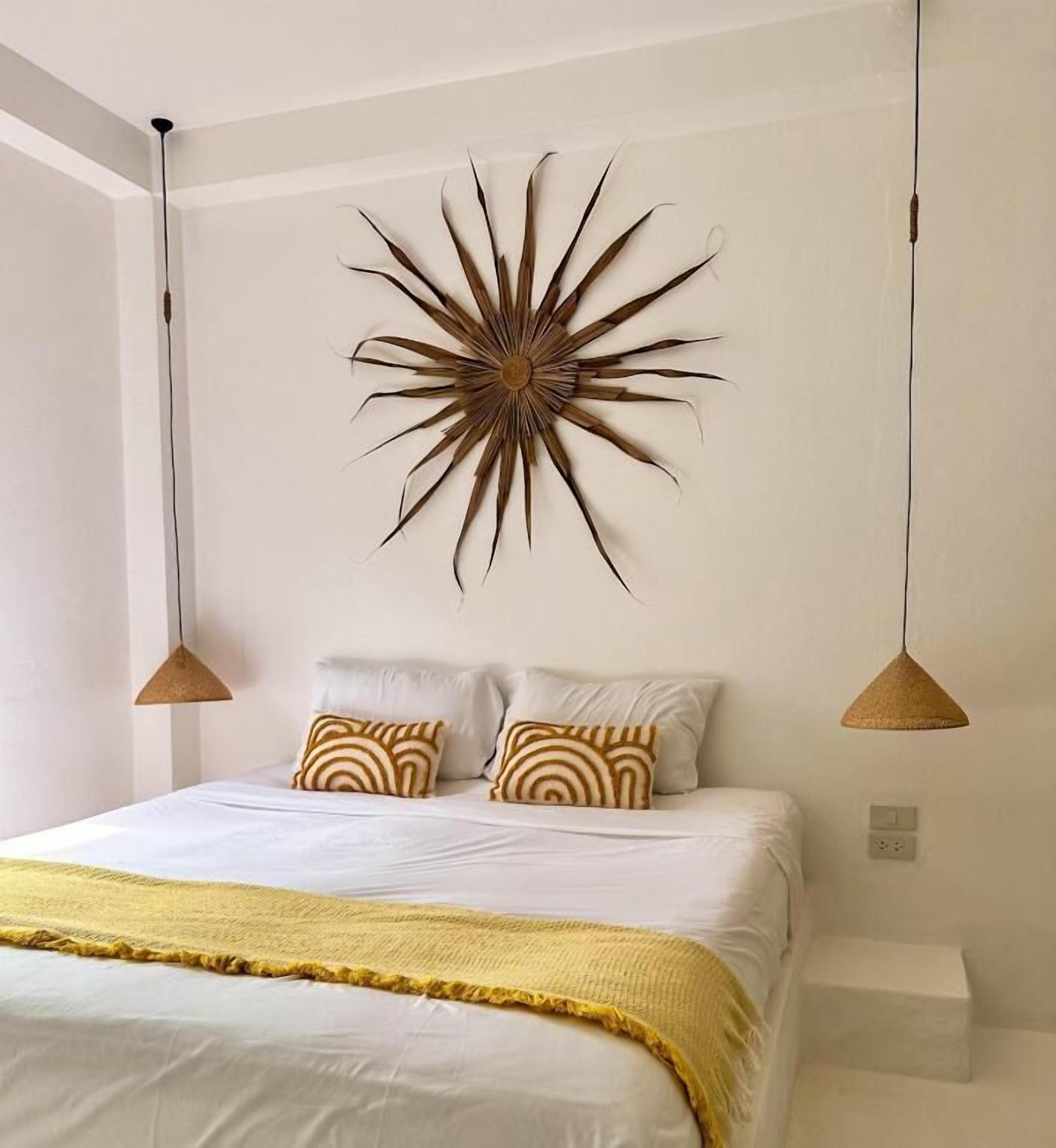 A bedroom with a bed, two bedside lamps, a wall-mounted decor piece, and a bedside table.