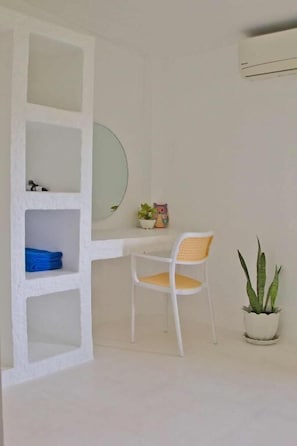 A room with a white desk, a chair, a potted plant, and a shelf with a mirror and a small decorative item. - Lanta Secret House (Saladan subdistrict)
