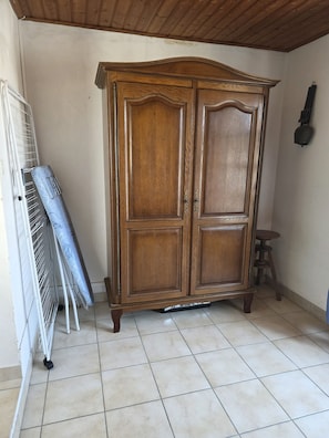 A room with a large wooden wardrobe, a white radiator, and a small stool. - A traditional Vendée house just a 5-minute walk from the beach! (Notre-Dame-de-Monts)
