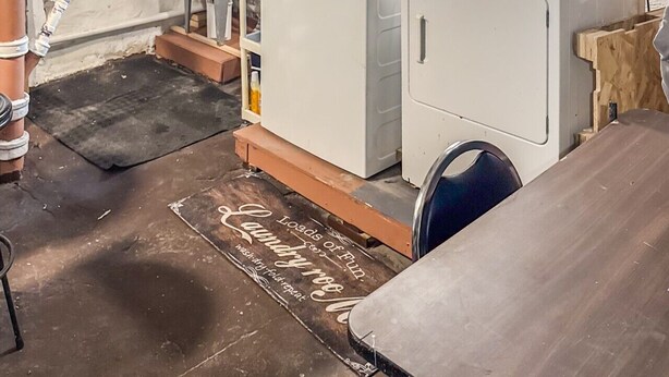A laundry room with industrial equipment, a metal table, and a vent.