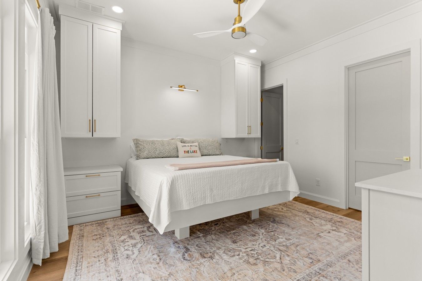 A bedroom with a bed, nightstands, a wardrobe, and a ceiling fan.