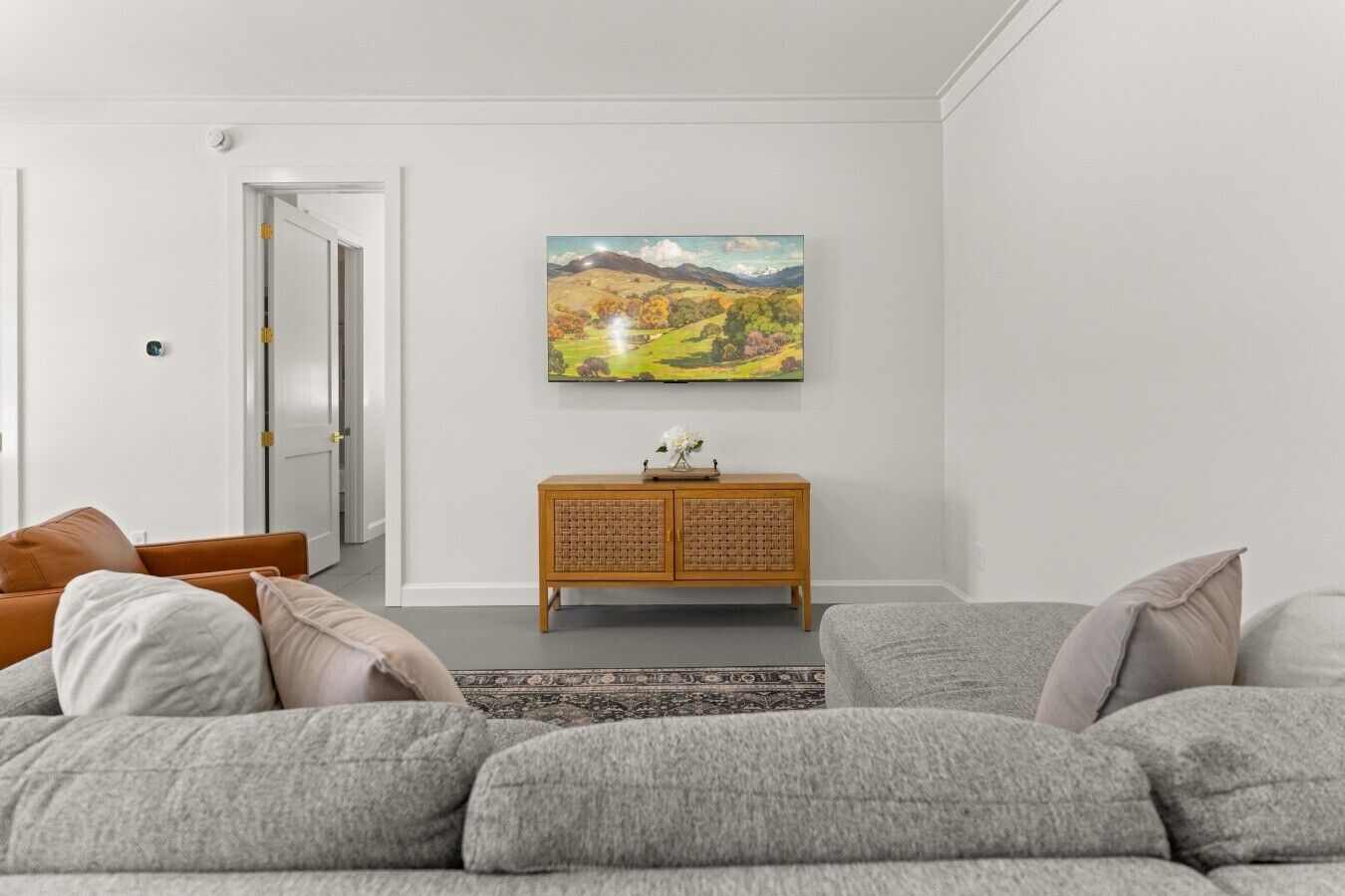 Ein Wohnzimmer mit grauem Sofa, einem Holzschrank und einem Bild an der Wand.