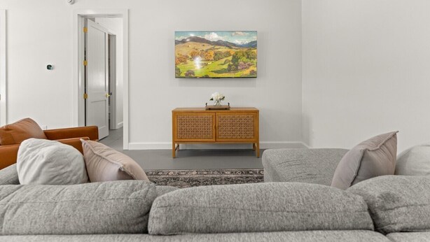 Ein Wohnzimmer mit grauem Sofa, einem Holzschrank und einem Bild an der Wand.