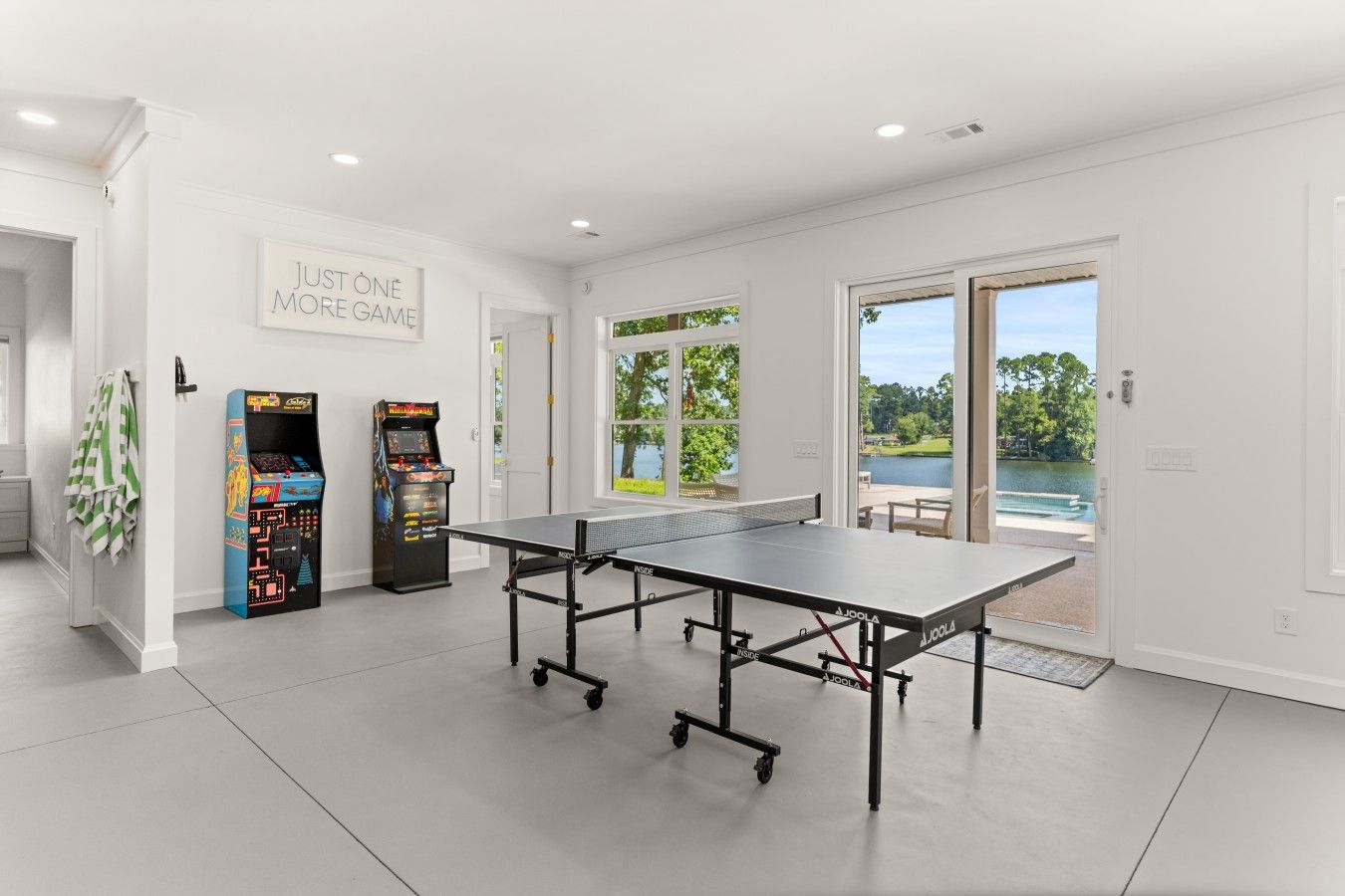 Una mesa de ping pong en una habitación con paredes blancas y un ventanal grande.