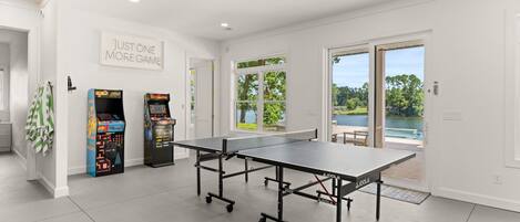 Una mesa de ping pong en una habitación con paredes blancas y un ventanal grande.
