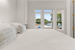 A bedroom with a large bed, a view of a swimming pool, and a door leading outside.