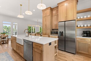 A modern kitchen with wooden cabinets, stainless steel appliances, and pendant lighting.