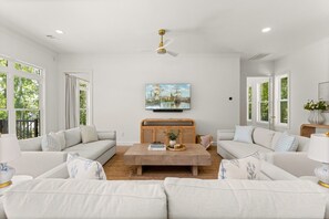 A spacious living room with two sofas, a coffee table, and a television mounted on the wall. - Lake Sinclair Dream Home w/ Everything|Pool|HotTub (Milledgeville)